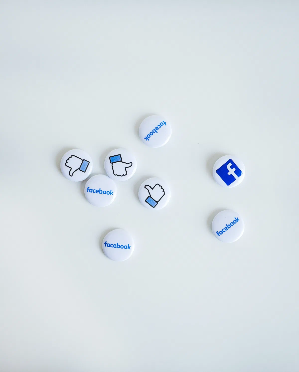 Traditional pin-back buttons with Facebook icons on them resting against a white background.